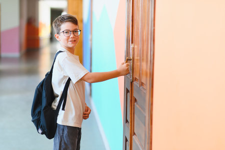 Young student with backpack opening the classroom door, excited for the school day and eager to learnの写真素材