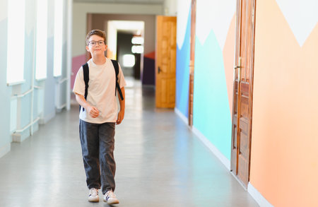 Boy with backpack walking in school hallway with colorful walls, going back to school after summer breakの写真素材