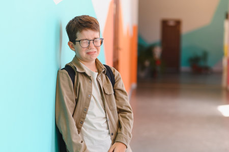 Sad schoolboy crying in school hallway because of bullying, child victim of bullying and discriminationの写真素材