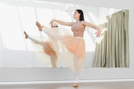 Graceful ballerina practicing a high kick in front of a mirror in a dance studio, showcasing her...