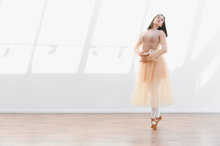 Young ballerina performing a graceful dance move in a bright studio, illuminated by natural lightの写真素材