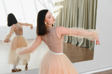 Young ballerina practicing graceful ballet moves in a dance studio, adorned in a tutu and elegant sleeves, showcasing dedication and artistryの写真素材