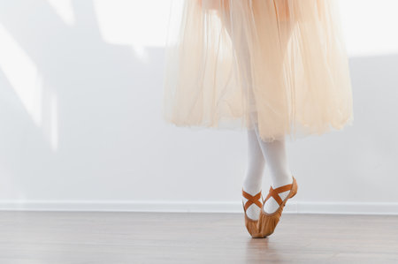 Young ballerina practicing ballet moves, standing on toes in dance studio, wearing a tutu and ballet shoes, showcasing grace and dedicationの写真素材