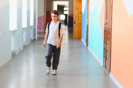 Schoolboy with a backpack walking through a bustling school corridor during break time, enjoying moments of childhood and camaraderieの写真素材