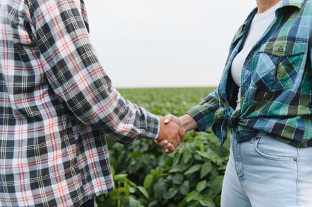 Two farmers are shaking hands in a soybean field, symbolizing partnership, trust, and successful collaboration in agricultureの写真素材