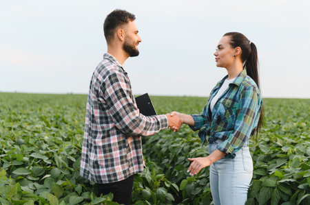 Agronomist and farmer shaking hands in a soybean field, making a deal for a new sustainable agriculture projectの写真素材