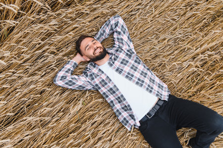 Young farmer resting in a golden wheat field, savoring a peaceful moment of contentment after a...