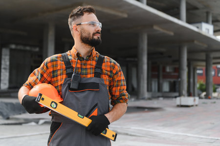 Experienced construction foreman in hard hat and safety gear overseeing commercial building site,...