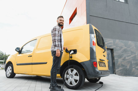Delivery driver charging electric van at station in city, promoting sustainable transportation and...