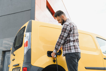 Delivery driver charging electric van at charging station, promoting sustainable transportation and eco friendly delivery servicesの写真素材