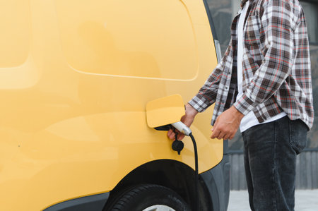 Delivery driver charging electric van promoting sustainable transportation and eco friendly delivery service in urban areasの写真素材