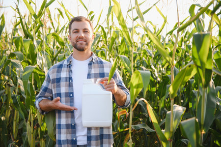 Farmer presenting a bottle of pesticide in a corn field, ensuring crop protection and healthy growthの写真素材