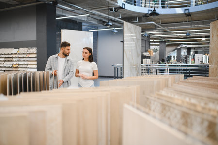 Young couple shopping for ceramic floor tiles, making decisions for their home renovation project in a large building materials storeの写真素材