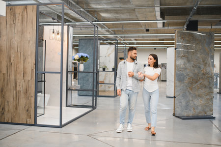 Young couple exploring a tile and flooring showroom, discussing choices for home improvement and remodeling renovation projectsの写真素材