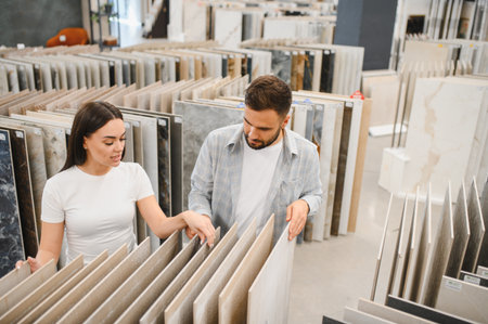 Young couple looking at samples of ceramic and porcelain tiles for their new home, planning interior design for a modern updateの写真素材