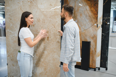 Young couple discussing tile options for flooring or wall covering, planning home improvement in a modern storeの写真素材