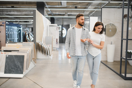 Young couple walking through a tile showroom, choosing materials for their house renovation project, discussing optionsの写真素材