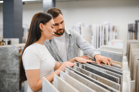 Young couple selecting new tiles for home improvement project. Shopping at a hardware store for their house modernizationの写真素材