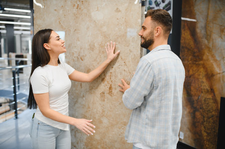 Young couple shopping for building materials, touching large marble slab at a home improvement store, making a decisionの写真素材