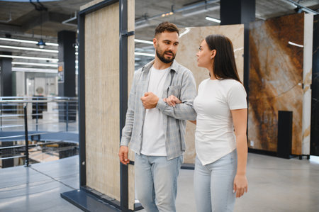Couple having a conversation while choosing new ceramic tiles in a showroom, planning their home renovationの写真素材