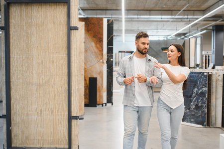 Young couple discussing and pointing, selecting new tiles for a home improvement project at a ceramic storeの写真素材
