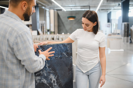 Man and woman examining dark blue marble tile in a store, making decisions for their home improvement projectの写真素材