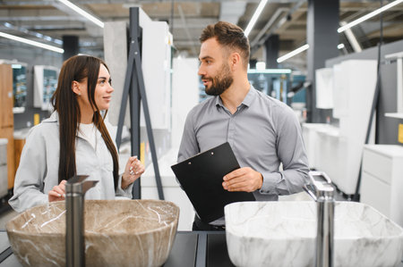 Woman customer and male sales assistant looking at a bathroom sink, choosing new fixtures for home renovationの写真素材