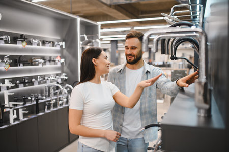 Young couple shopping for plumbing fixtures in a hardware store. Selecting kitchen or bathroom faucets for renovationの写真素材