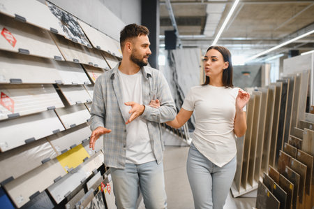 Young couple shopping for building materials, discussing choices for their new home improvement project in a store showroomの写真素材
