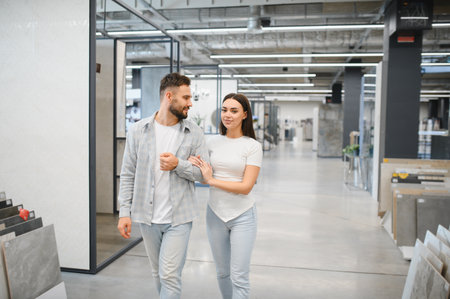 Couple walking arm in arm, shopping for new tiles for home renovation in a large modern hardware storeの写真素材