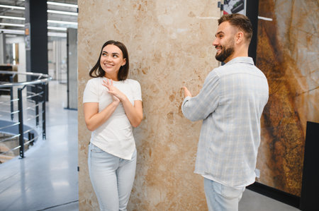 Young happy couple shopping for new home renovation, selecting marble look tiles in a modern construction materials storeの写真素材