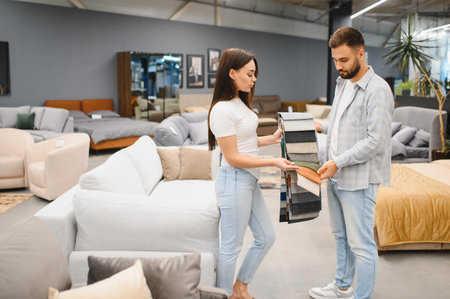 Young couple comparing fabric samples in a furniture store, deciding on upholstery for their new home, buying furnitureの写真素材