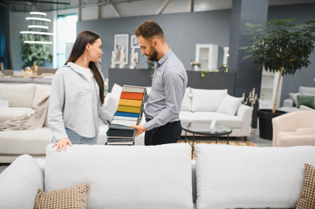 Woman and sales consultant discussing fabric swatches for new furniture in a modern retail store, focusing on home decor choicesの写真素材