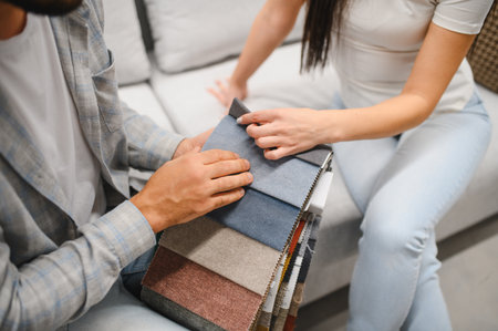 Couple hands reviewing furniture fabric samples for sofa upholstery, making interior design decisionsの写真素材