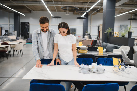 Young couple looking at a modern dining table, planning home improvement and furnishing new apartmentの写真素材