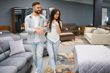 Young couple a browsing modern furniture showroom, smiling as they choose sofas and decor while planning their future home togetherの写真素材