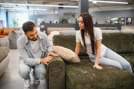 Young couple shopping, comparing, and deciding on a sofa for their home. Buying furniture for living roomの写真素材