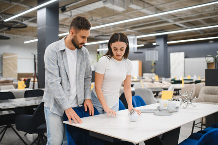 Young couple shopping, comparing, and choosing new dining furniture for their home in a modern storeの写真素材