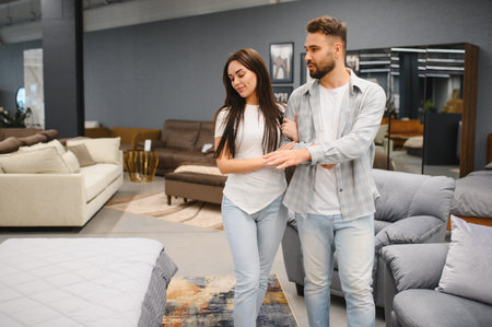 Young couple looking for new furniture, choosing bedding for their home. Buying new home goods in a retail storeの写真素材