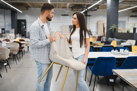 Happy couple inspecting a chair in a modern furniture store, making decisions for their new house interior designの写真素材