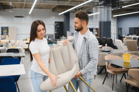 Young couple shopping in a furniture store, looking at chairs for their new home, making a purchasing decisionの写真素材