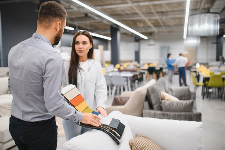 Sales consultant showing fabric swatches to a female customer in a modern furniture showroom, assisting with upholstery selectionの写真素材