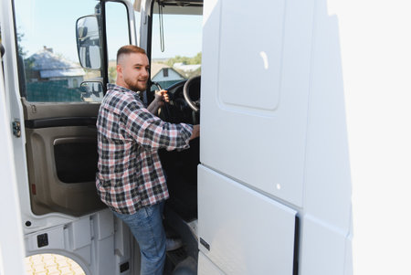 Young man in plaid shirt stepping into a large transport truck, preparing for a journey. Concept of road freight and deliveryの写真素材