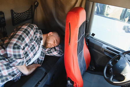Professional truck driver resting in the cabin of heavy freight vehicle, taking a break from long haul journeyの写真素材