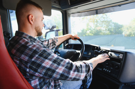 Truck driver operating vehicle controls inside cabin. Representing transportation, logistics, and professional driving occupationの写真素材