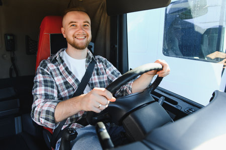 Smiling young man driving a heavy goods vehicle, symbolizing professional transportation, logistics, and deliveryの写真素材