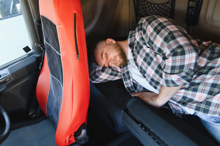 Truck driver sleeping peacefully in sleeper cabin during long haul break, resting between shifts on interstate freight journeyの写真素材