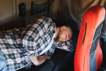 Male trucker sleeping on bunk bed inside a truck cabin during a long haul, getting necessary rest and avoiding fatigueの写真素材