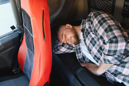 Truck driver catching sleep in sleeper cab during a long haul break, resting peacefully inside the vehicle's compact bedの写真素材