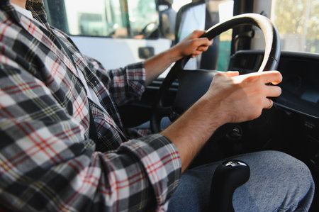 Man in a flannel shirt driving a truck, hands on the steering wheel, managing transportation and logisticsの写真素材